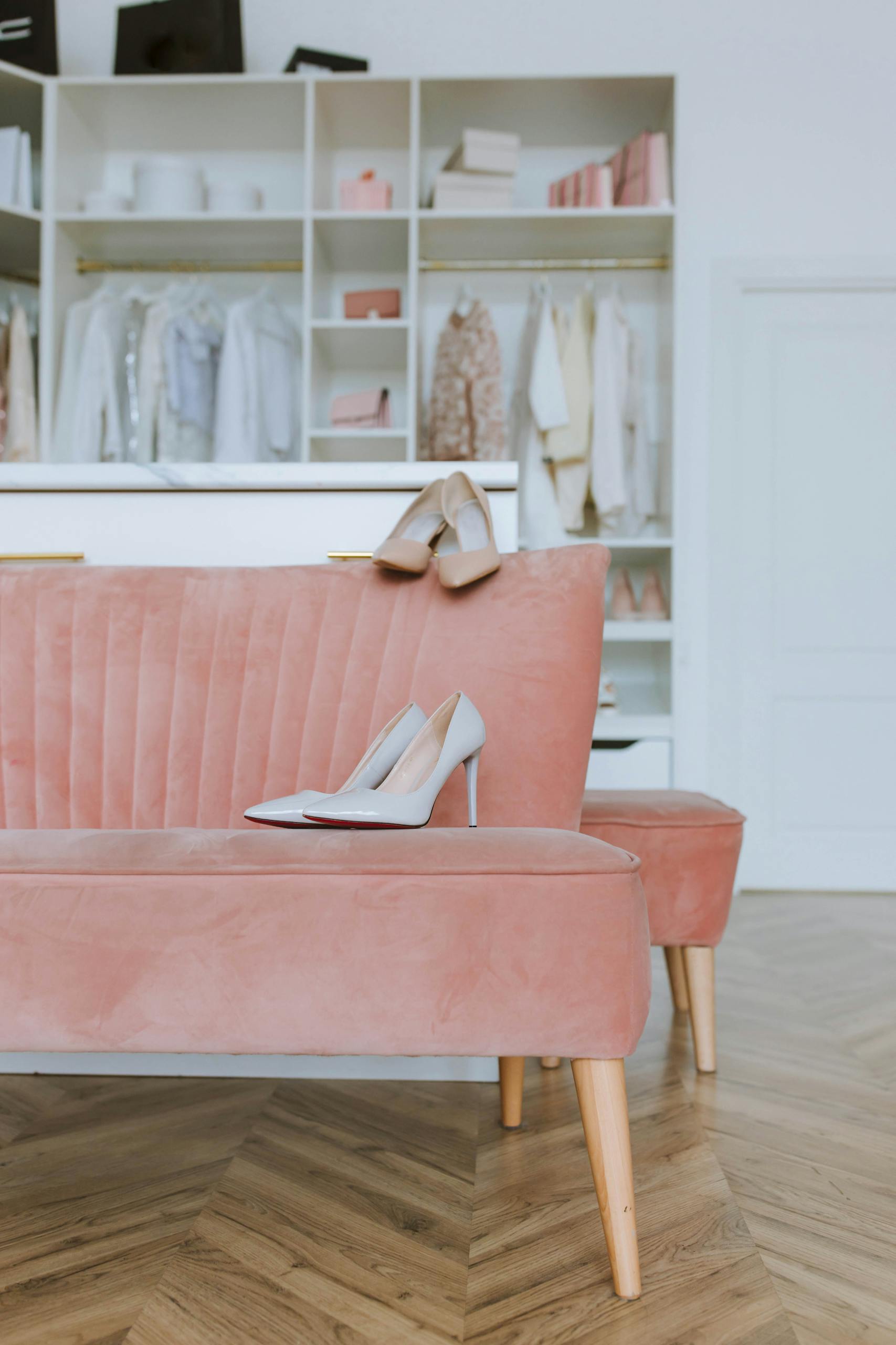 Stylish high heels on a pink sofa in a chic walk-in closet, showcasing glamour and sophistication.