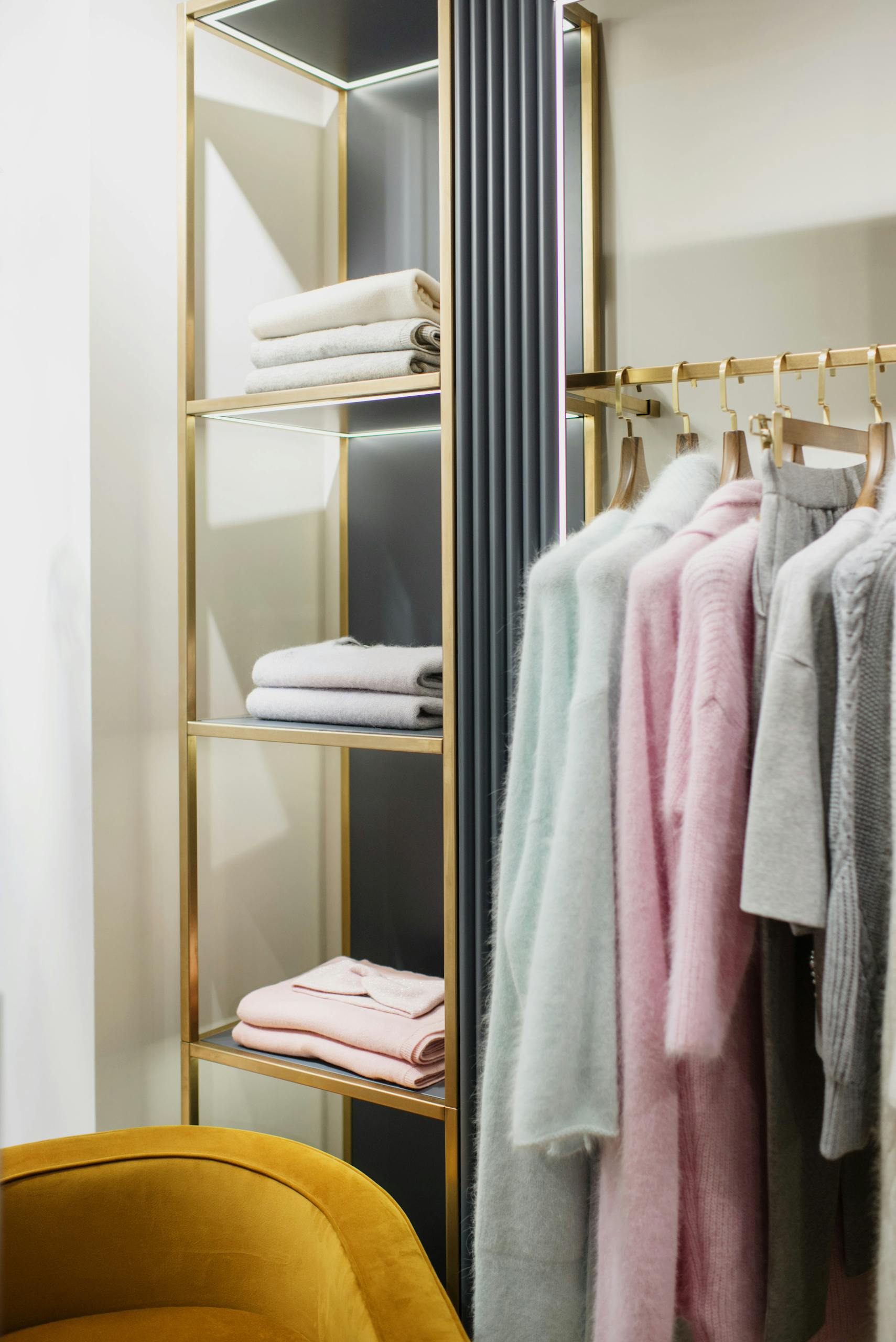 Stylish wardrobe featuring pastel clothing and neatly folded towels on elegant shelves.